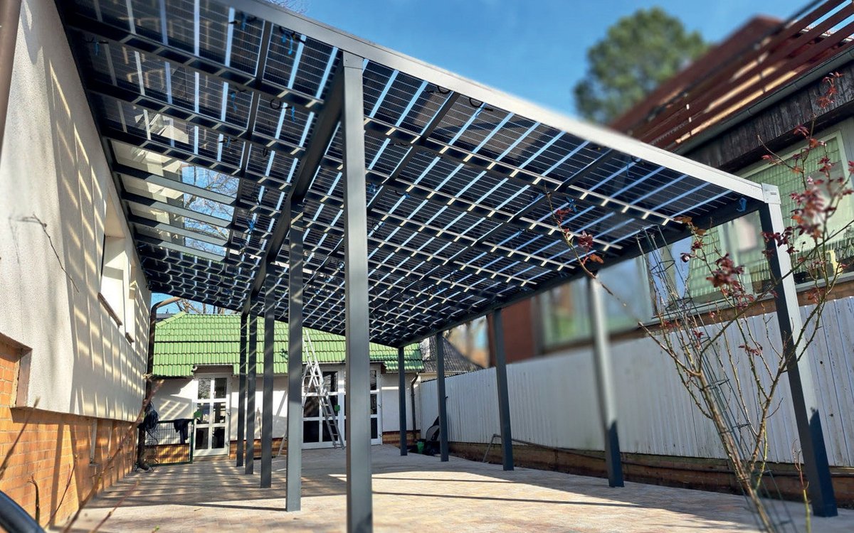 Aluminium-Solarcarport, an eine Hauswand angelehnt, über einem gepflasterten Hof