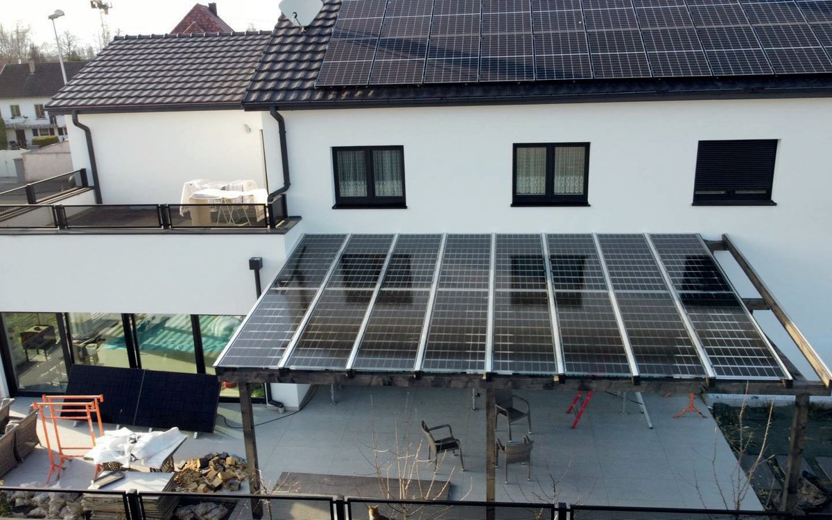 Luftbild: Solarterrasse auf einer Holzkonstruktion vor einem Haus mit Photovoltaik auf dem Dach